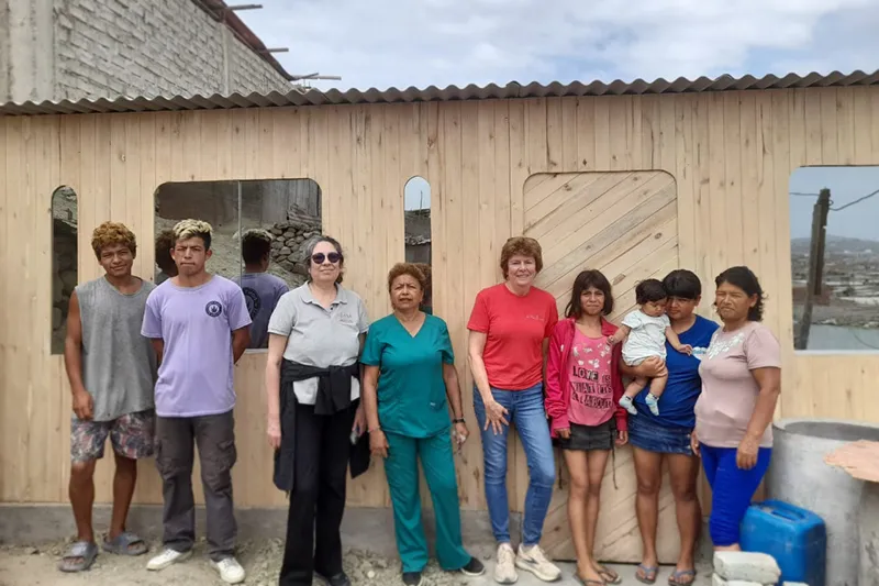 Family with Volunteers and workers standing in front of a newly built home
