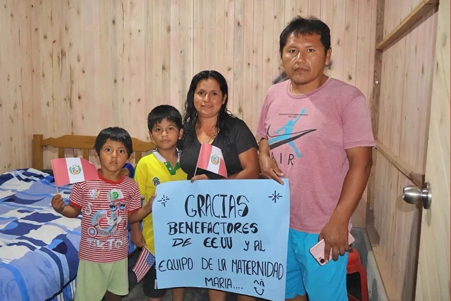 Gustavo Cuba and Dany Ruiz with their three children holding a thank you sign in their new home